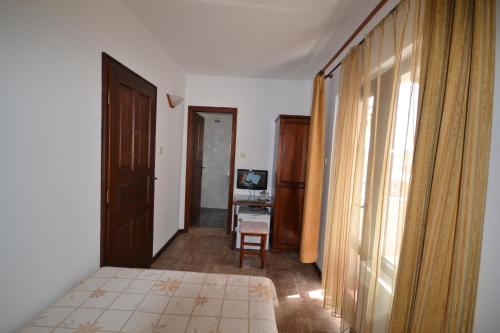 a bedroom with a bed and a desk and a window at More Family Hotel in Sozopol