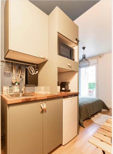une cuisine avec des armoires blanches et un évier et un lit dans l'établissement Le Garden Studio avec terrasse et parking centre ville, à Rouen