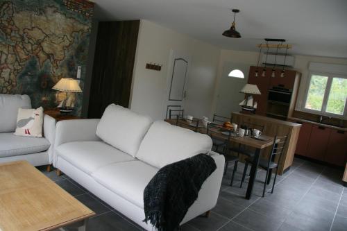 a living room with a white couch and a kitchen at Le Domaine de Louise in Seigy