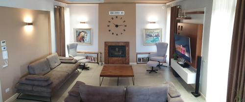 a living room with a couch and a clock on the wall at HILLTOP HIDEAWAY in Elbasan