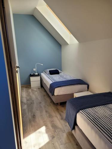 a bedroom with two beds with blue walls and wooden floors at DĘBKI DOMKI SASANKOWE in Dębki