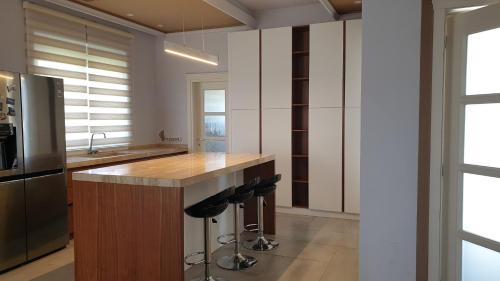 a kitchen with a counter with a refrigerator and stools at HILLTOP HIDEAWAY in Elbasan