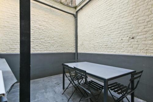 Large and calm flat in the heart of Lille - Welkeys في ليل: طاولة وكراسي في غرفة بجدار من الطوب