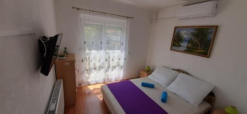 ein kleines Schlafzimmer mit einem Bett und einem Fenster in der Unterkunft Major apartman in Kehidakustány