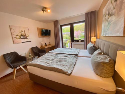 a bedroom with a bed and a chair and a window at Landhotel Fasanenhof in Eschwege