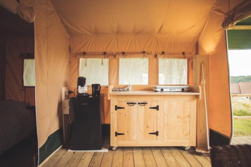 uma pequena cozinha numa tenda com um frigorífico em Le Noyer em Rougnat