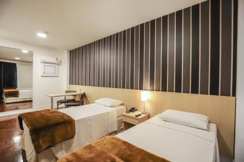 um quarto de hotel com duas camas e uma secretária em 155 Hotel em São Paulo