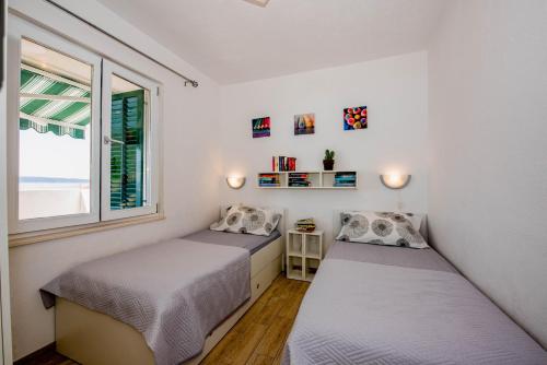 two beds in a room with a window at Apartment Zora in Trogir