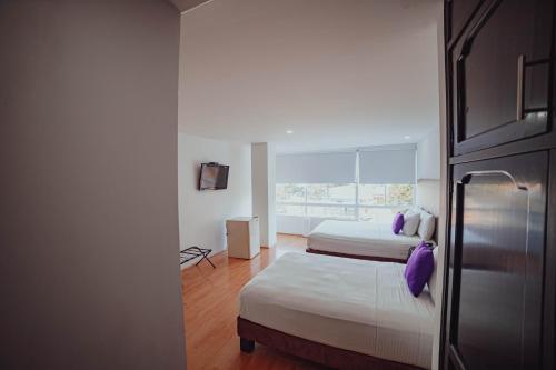 a hotel room with two beds and a refrigerator at Hotel Metropolis Plaza Cali in Cali