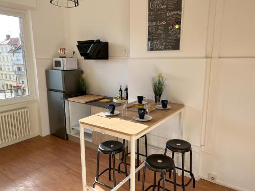 a small kitchen with a table and stools at Chambres privées -Private room- dans un spacieux appartement - 100m2 centre proche gare in Mulhouse