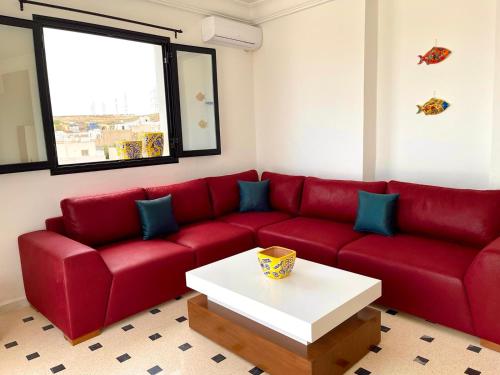 a red couch in a living room with a coffee table at Soltane Résidence in Hammamet