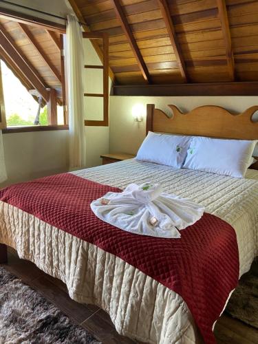 a bedroom with a bed with a robe on it at Chales Elliotti in Monte Verde