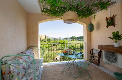 a room with a bed and a balcony with a table at Le PTIT OLIVIER piscine - plage in Gassin