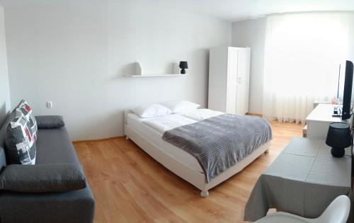 a white bedroom with a bed and a couch at Pokoje Gościnne Alpinka in Ustka