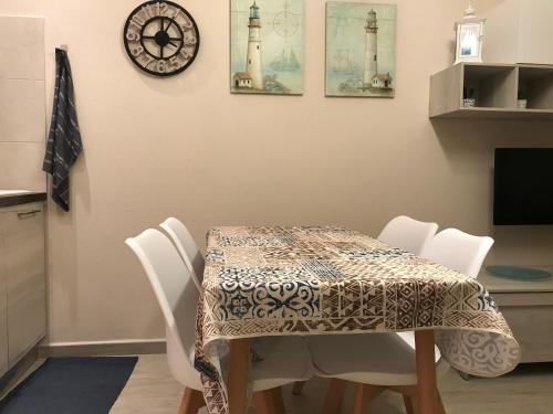 a dining room table with white chairs and a clock at Alghero casa con piscina lido fronte mare in Alghero