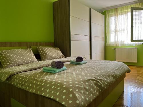 1 dormitorio verde con 1 cama con 2 toallas en Apartman Ruby, en Doboj