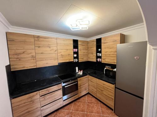cocina con armarios de madera y nevera en Apartman Ruby, en Doboj