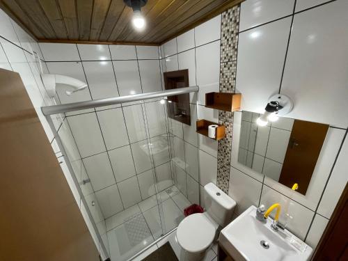 a bathroom with a shower and a toilet and a sink at Suites Hencke Haus in Canela