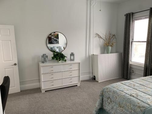 a white bedroom with a dresser and a mirror at Stylish 2BD/1BA apartment located in Federal Hill in Baltimore