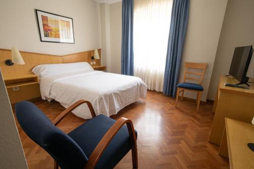 Habitación de hotel con cama, silla y TV en Hotel Bracamonte, en Peñaranda de Bracamonte