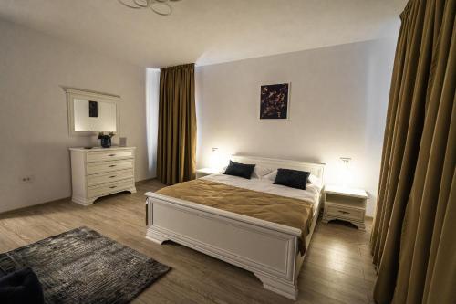 a bedroom with a white bed and a dresser at Armada Aparthotel in Alba Iulia