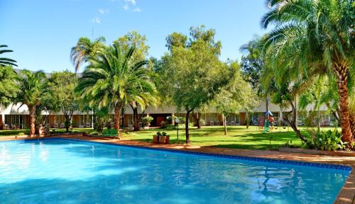 a swimming pool with palm trees in the background at Sundown Country Estate in Boshoek