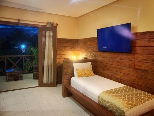 a bedroom with a bed and a television on the wall at Pousada Oasis Paracuru in Paracuru