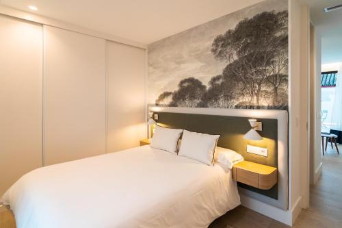 a bedroom with a white bed and a painting on the wall at CISNES PALACE in Sanlúcar de Barrameda