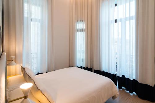 a white bed in a room with windows at CISNES PALACE in Sanlúcar de Barrameda