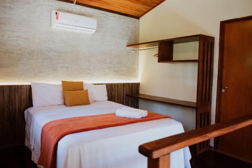 Dormitorio pequeño con cama con manta naranja en Vila do Porto, Praia do Patacho - Bangalô Milagres en Pôrto de Pedras