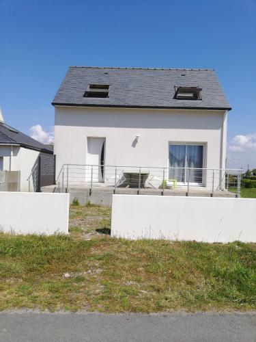 una casa blanca con una valla delante en Maison bord de mer, en Penmarch