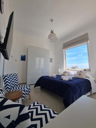 sypialnia z niebieskim łóżkiem i oknem w obiekcie Casa Leucosia Suites w mieście Capri
