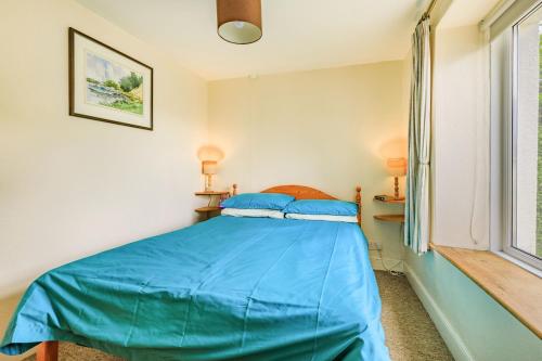 a bedroom with a bed with blue sheets and a window at Whitestone in Ilfracombe