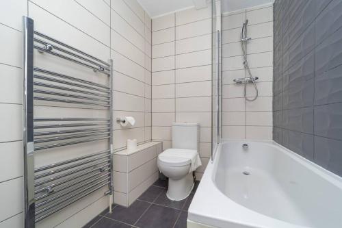 a white bathroom with a toilet and a bath tub at TROPICAL SUNNY 2 BED FLAT SEAFRONT Slp 6 in Brighton & Hove