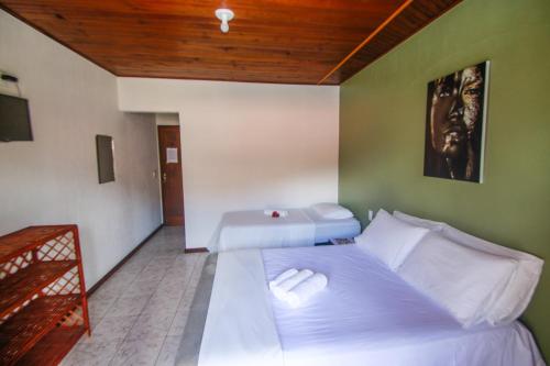 a bedroom with two beds and a wooden ceiling at Pousada da praça in Morro de São Paulo
