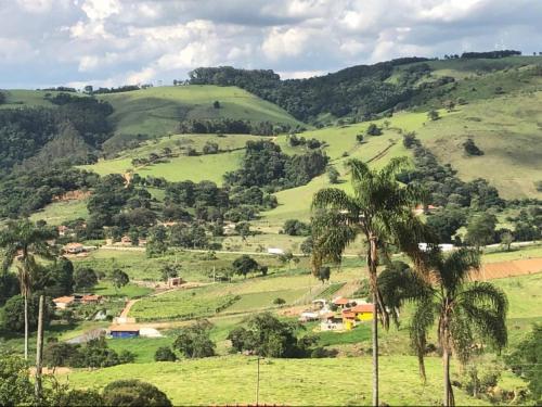 a view of a green hillside with palm trees at Sítio no interior de SP para curtir a Natureza in Águas da Prata