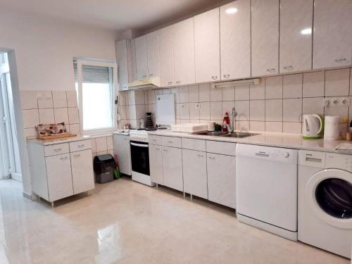 a kitchen with white cabinets and a sink and a dishwasher at Apartman Square in Mostar