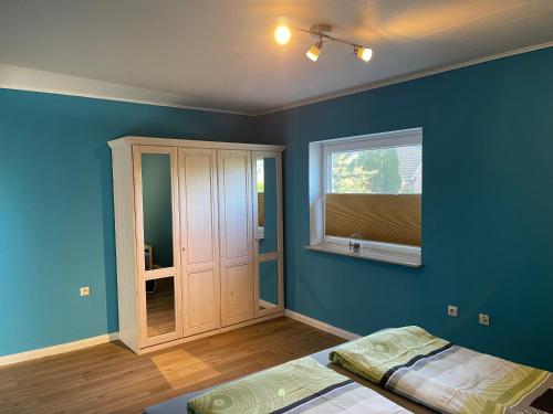 een slaapkamer met blauwe muren, een kast en een raam bij Haberstraße 4A Neumünster in Neumünster