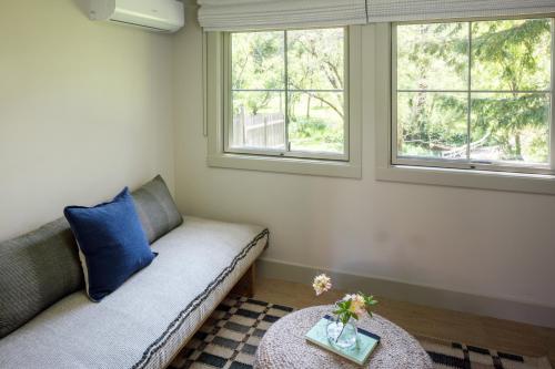a living room with a couch and two windows at Dawn Ranch in Guerneville