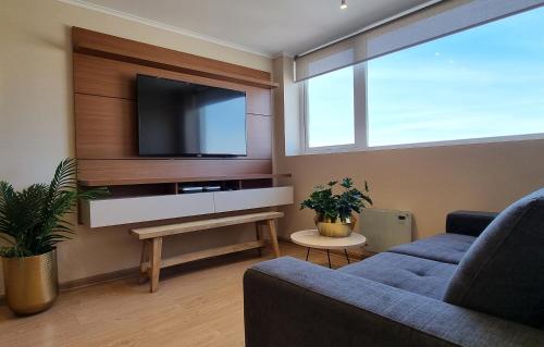 a living room with a tv on a wall at Apart Hotel Las Terrazas Suite in Chillán