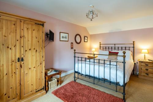 HolkerにあるAmber Cottageのベッドルーム1室(ベッド1台付)、木製キャビネットが備わります。