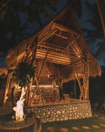 two people standing in front of a bamboo house at La royale Romantic Bamboo Villas in Klungkung