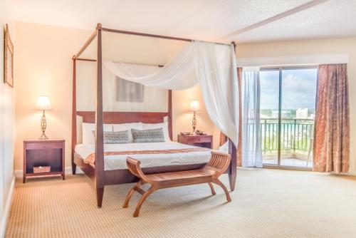 a bedroom with a canopy bed and a chair at Holiday Resort & Spa Guam in Tumon
