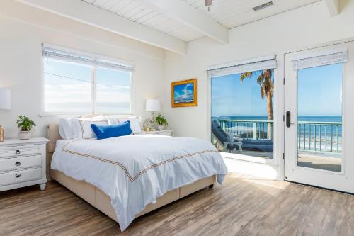 a bedroom with a bed and a balcony with the ocean at Brink of Paradise in Carpinteria