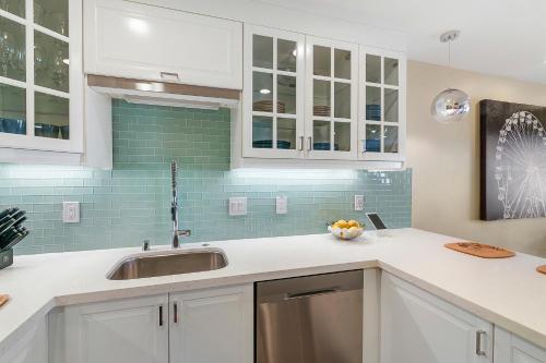a kitchen with white cabinets and a sink at Doorstep to Disneyland Condos in Anaheim