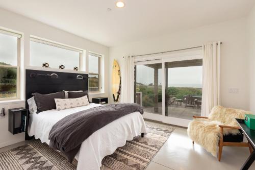 een slaapkamer met een bed, een stoel en ramen bij Heron Manor in Bodega Bay
