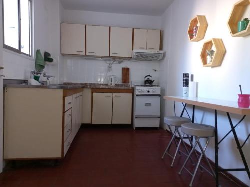 a kitchen with white cabinets and a table and stools at Departamento San Lorenzo para 4 personas in Mendoza
