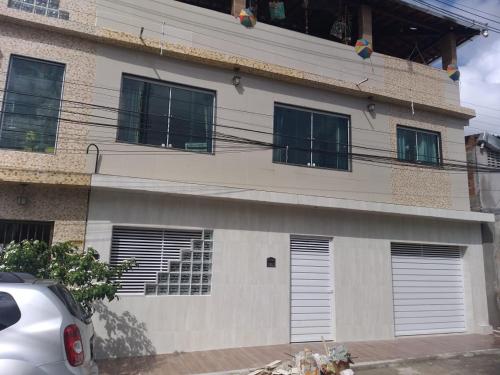 a building with shuttered windows and a car parked in front at Florcamará POUSADA in Camaragibe