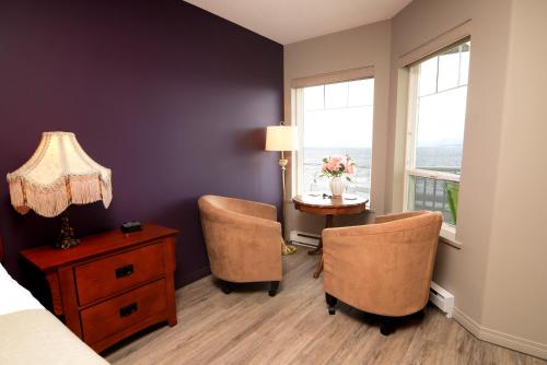 a bedroom with a table and two chairs and a window at Casa Grande Inn in Qualicum Beach