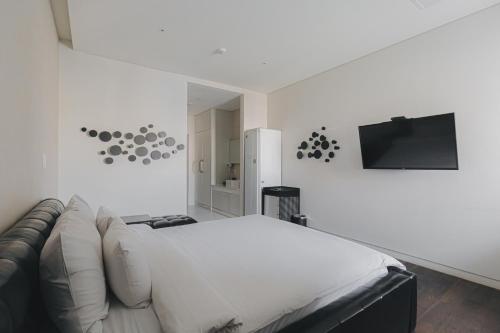 a white bedroom with a couch and a flat screen tv at ACC Design Hotel in Gwangju